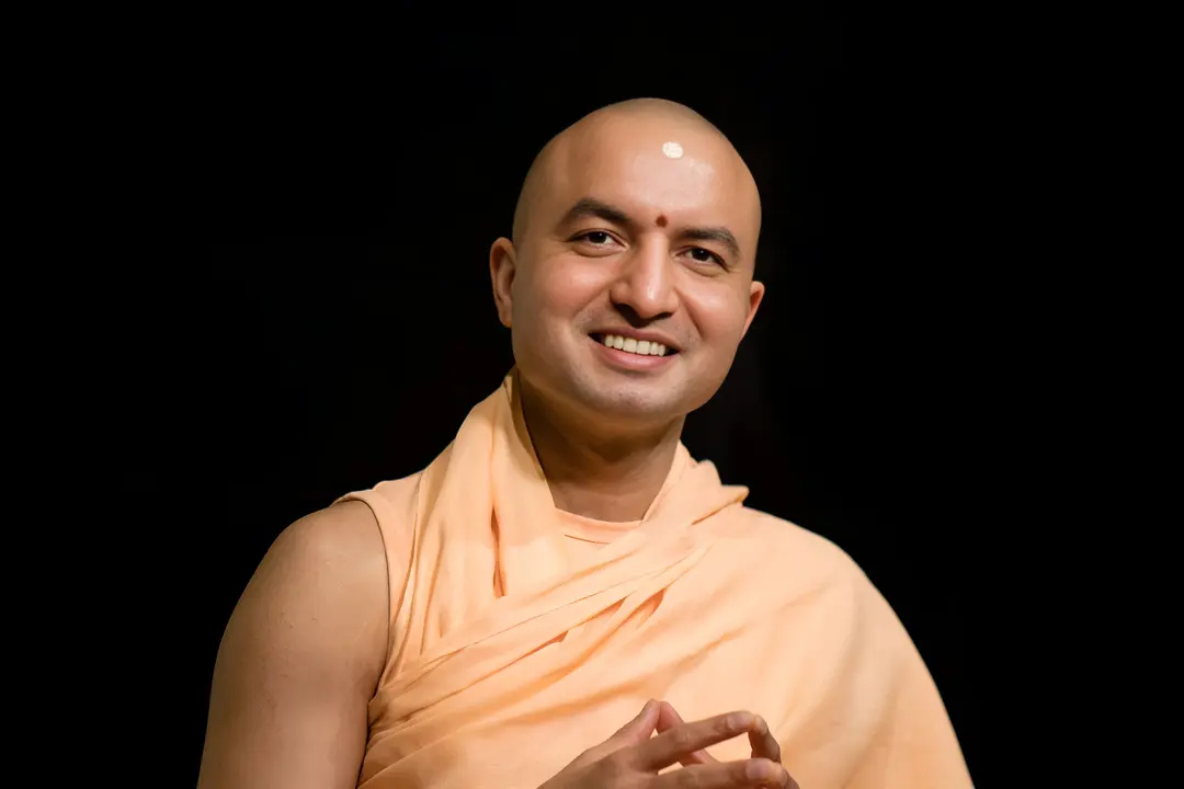 Om Swami smiling, in saffron robes, hands gently joined
