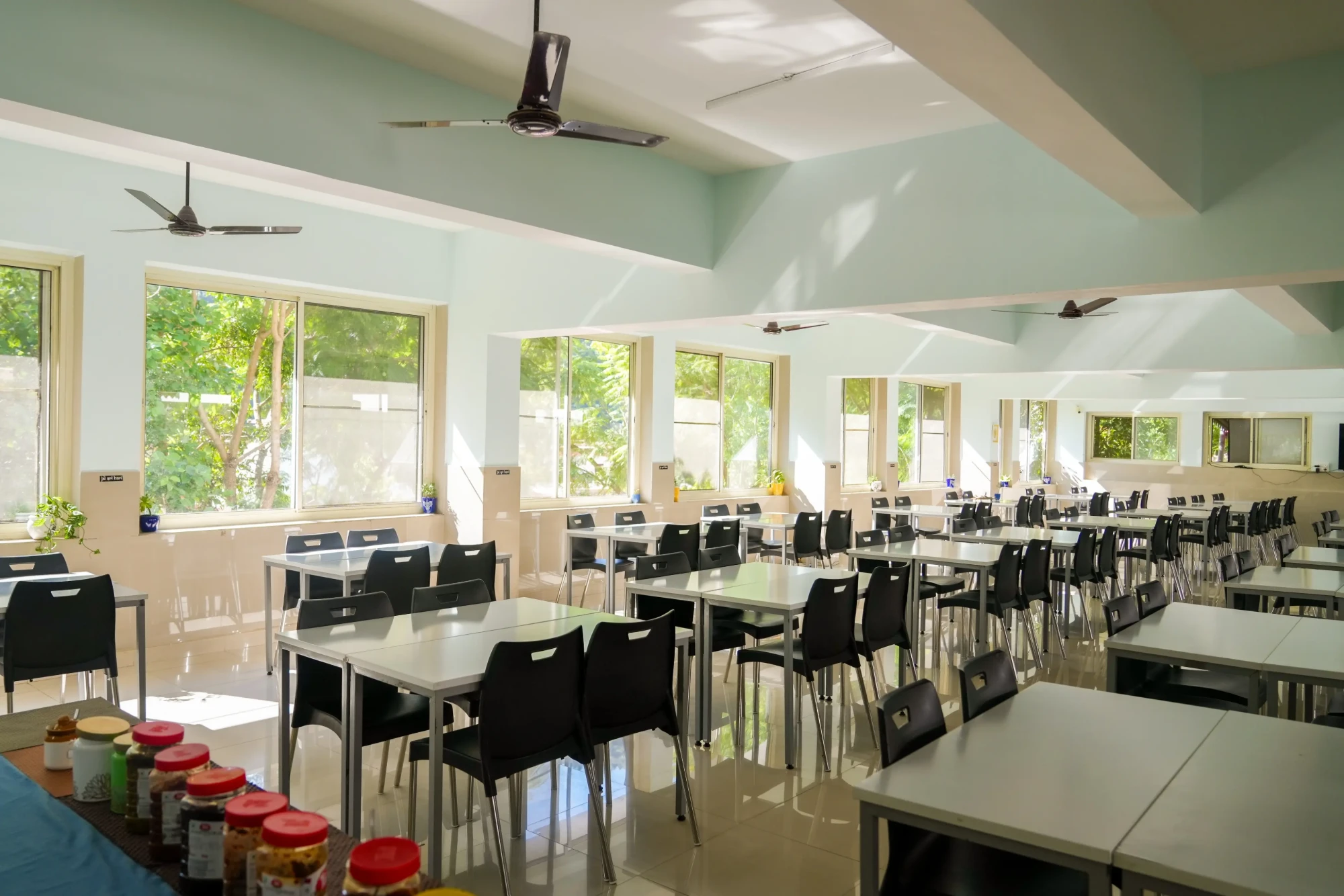 The sunlit dining hall with rows of tables and chairs