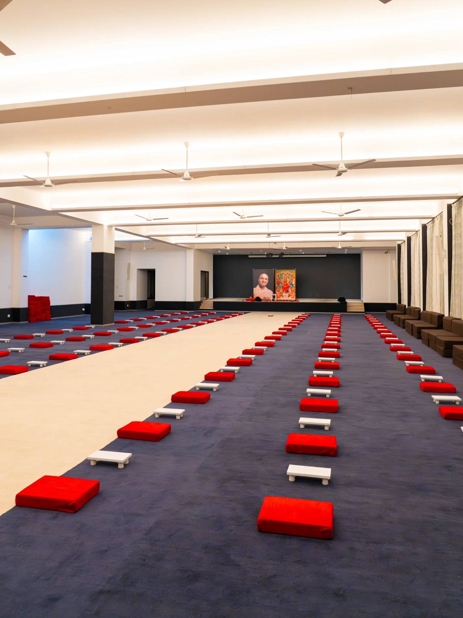 The meditation hall with rows of red cushions facing the stage